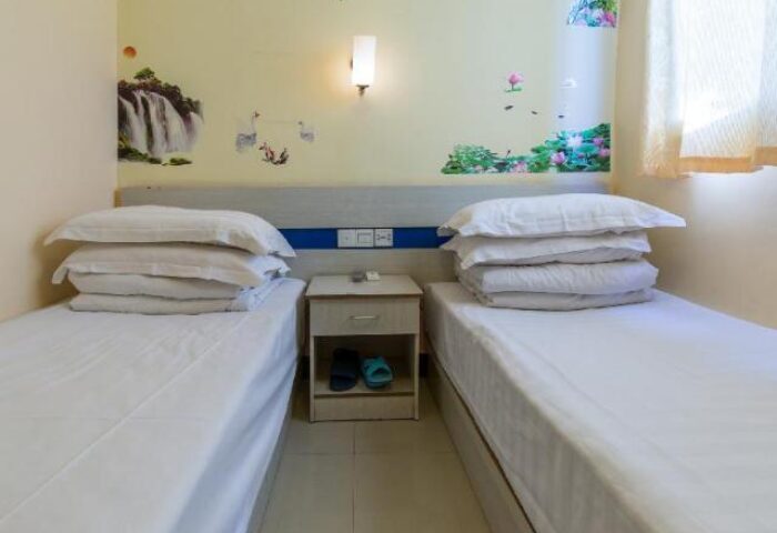 Happy Dragon Backpackers Hostel room. Twin beds with white linens, nightstand, wall art. Gay-friendly hotel for gay men travelers.