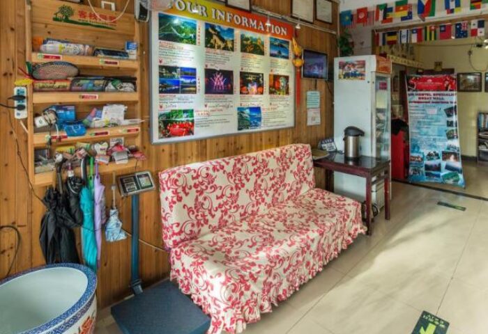Happy Dragon Backpackers Hostel interior. Gay-friendly hotel with info board, floral couch, and flags. Ideal for gay travel advice.