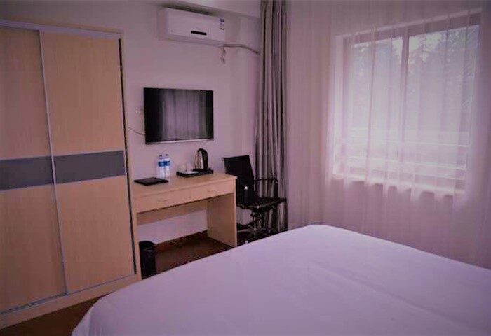 Harcourts Kailun Hotel room. Gay-friendly hotel bedroom with a bed, desk, TV, wardrobe, and window. Modern interior design for gay travelers.