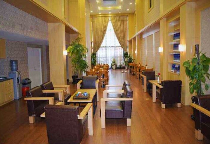 Harcourts Kailun Hotel interior. A gay-friendly hotel with a spacious lounge area, tables, chairs, and a view of the dining area.