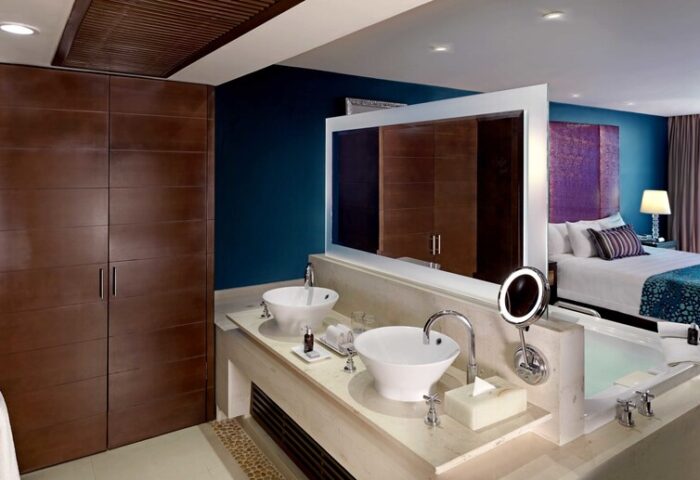 Hard Rock Hotel Cancun All Inclusive bathroom. Gay-friendly hotel room with double sinks, tub, and bedroom view. Luxury travel.