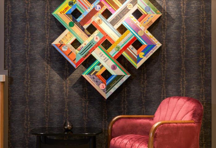 Hard Rock Hotel Dublin art. Gay-friendly hotel decor with colorful geometric wall art above a red velvet chair and small table. Dublin travel.