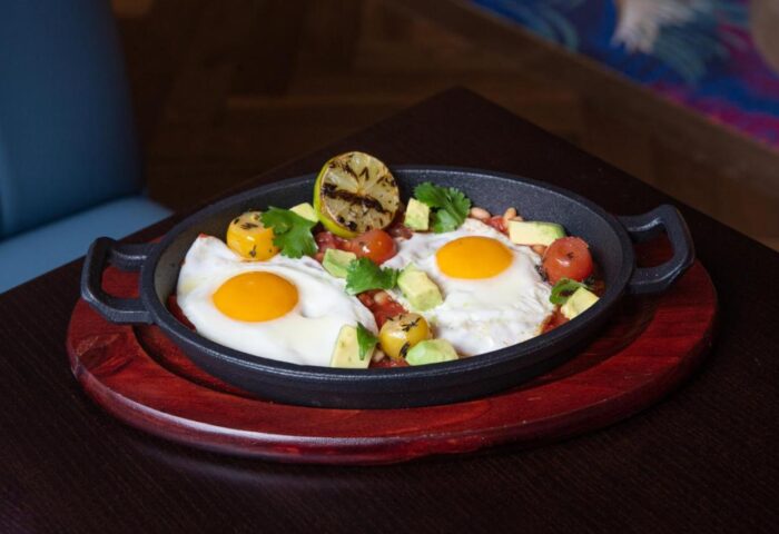 Breakfast skillet at Hard Rock Hotel Dublin, a gay-friendly hotel. Sunny-side up eggs with avocado, tomatoes, beans, and grilled lime.