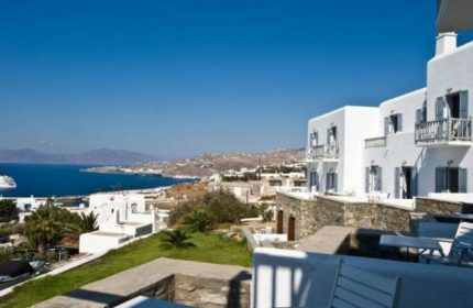 Hermes Mykonos Hotel view. Gay-friendly hotel with whitewashed buildings, balconies, and sea view. A perfect gay travel destination in Mykonos.