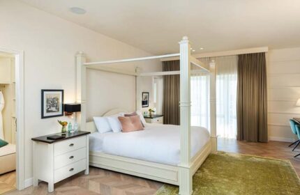 Herods Tel Aviv By The Beach gay-friendly hotel room. Four-poster bed, white linens, and pink pillows. Beach view. Luxury gay travel.