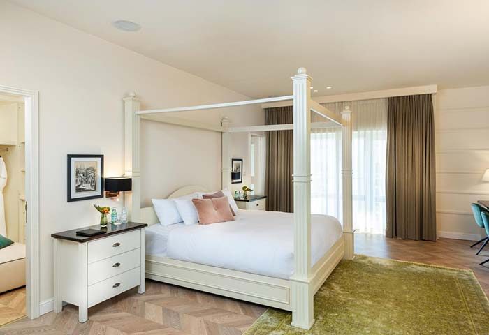 Herods Tel Aviv By The Beach gay-friendly hotel room. Four-poster bed, white linens, and pink pillows. Beach view. Luxury gay travel.