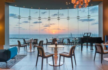 Herods Tel Aviv By The Beach hotel interior with sunset view. Gay-friendly hotel lounge with piano. Perfect for gay travel in Tel Aviv.
