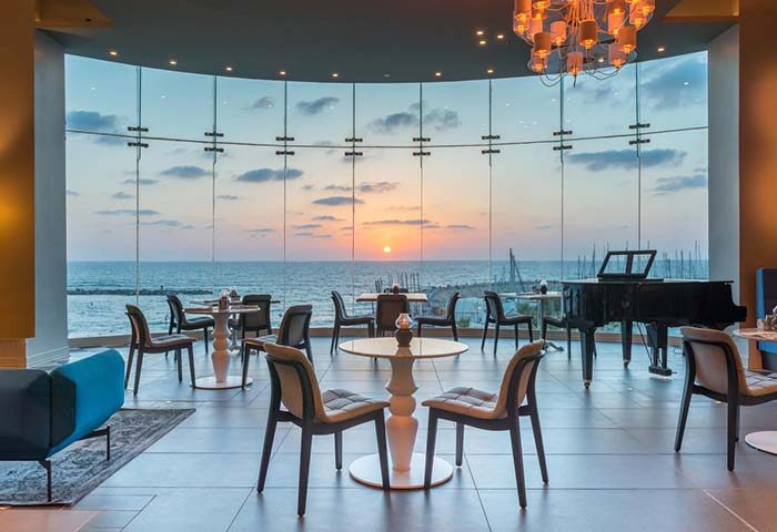 Herods Tel Aviv By The Beach hotel interior with sunset view. Gay-friendly hotel lounge with piano. Perfect for gay travel in Tel Aviv.