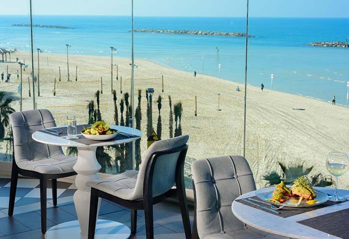 Herods Tel Aviv By the Beach: Dining with a view at this gay-friendly hotel. Tables set for meals overlook the beach and Mediterranean Sea.