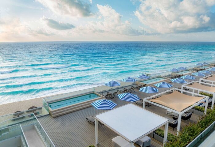 Hilton Cancun Mar Caribe All-Inclusive Resort ocean view. Gay-friendly hotel with beach umbrellas, pools, and lounge areas.