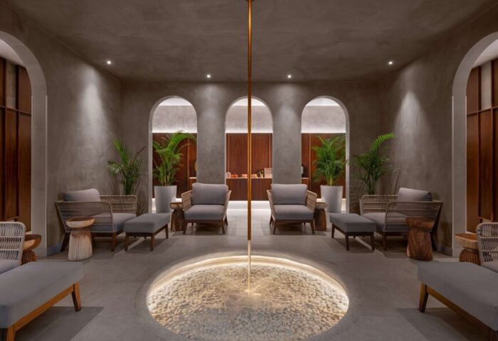 Hilton Cancun Mar Caribe All-Inclusive Resort interior. Lounge area with seating, plants, and a unique water feature. Gay-friendly hotel.