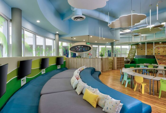 Kids club at Gay-Friendly Hilton Cancun Mar Caribe All-Inclusive Resort. Play area with tables, chairs, climbing wall, and TV screens.