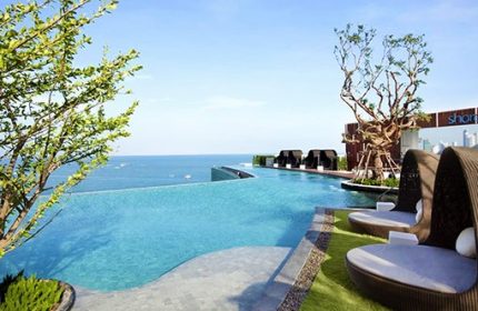 Hilton Pattaya gay-friendly hotel infinity pool view. Loungers, ocean, and blue sky create a relaxing atmosphere for gay travelers.