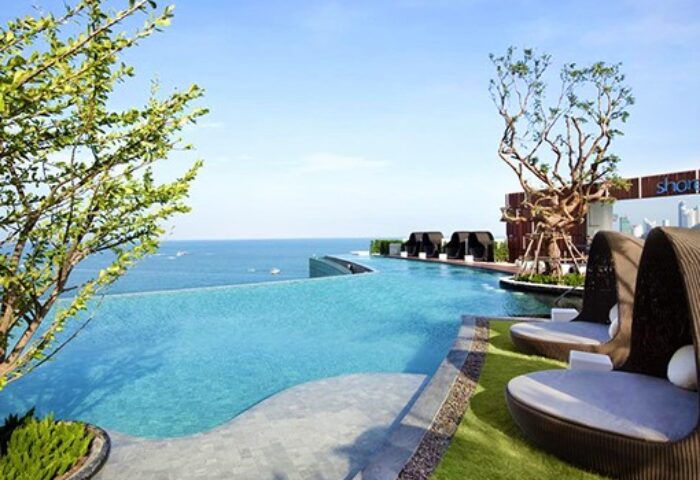 Hilton Pattaya gay-friendly hotel infinity pool view. Loungers, ocean, and blue sky create a relaxing atmosphere for gay travelers.
