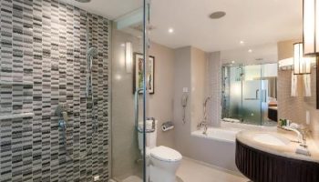 Bathroom at Hilton Phuket Arcadia Resort & Spa, a gay-friendly hotel. Features a shower, toilet, tub, and sink with a modern design.