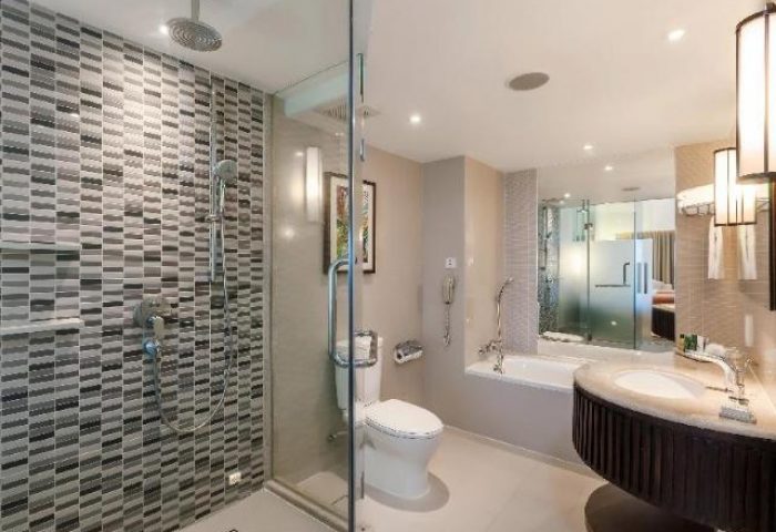 Bathroom at Hilton Phuket Arcadia Resort & Spa, a gay-friendly hotel. Features a shower, toilet, tub, and sink with a modern design.