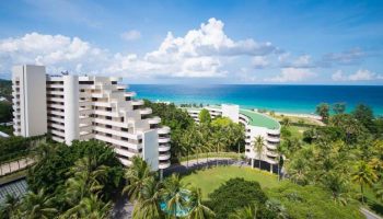 Hilton Phuket Arcadia Resort & Spa, a gay-friendly hotel. Aerial view of the resort, palm trees, beach, and ocean. Perfect for gay travel.
