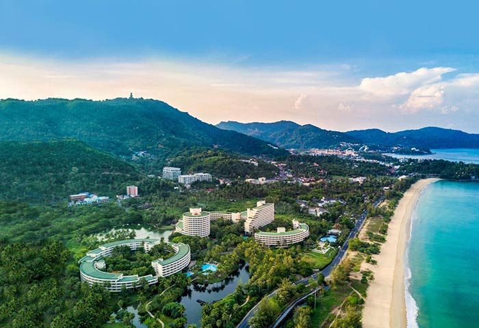 Gay-Friendly Hilton Phuket Arcadia Resort & Spa aerial view. Beachfront hotel with lush greenery, pools, and ocean views. Ideal gay travel spot.