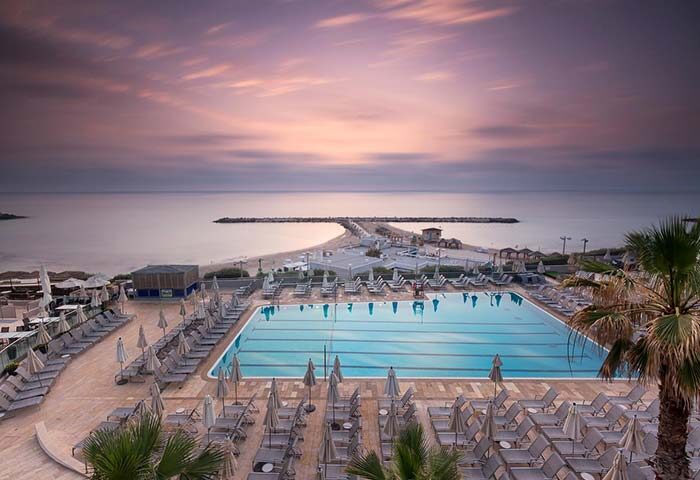 Hilton Tel Aviv gay-friendly hotel pool and beach view at sunset. A luxury travel destination for gay men in Tel Aviv, Israel.