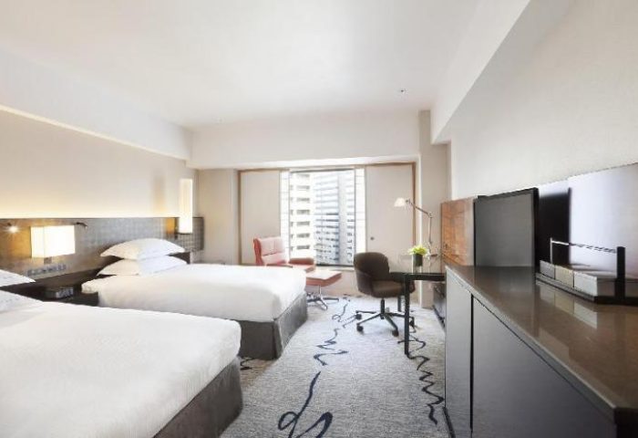 Hilton Tokyo hotel room with two beds, desk, and city view. This gay-friendly hotel offers comfortable accommodations for LGBTQ+ travelers.
