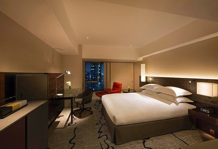 Hilton Tokyo hotel room. Gay-friendly hotel with a bed, desk, and city view. The room is well-lit and modern, perfect for gay travelers.