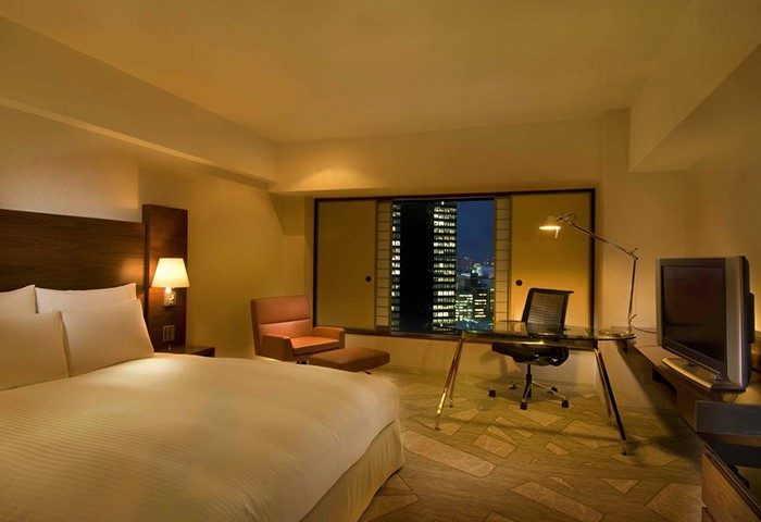 Hilton Tokyo hotel room interior. Gay-friendly hotel with bed, desk, chair, and city view. Modern design in a Tokyo hotel.