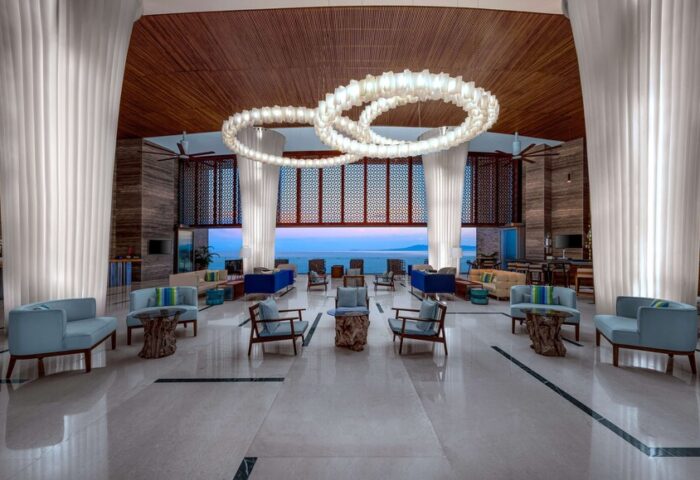 Hilton Vallarta Riviera All-Inclusive Resort lobby. Gay-friendly hotel with ocean view, stylish seating, and modern lighting. Luxury travel.