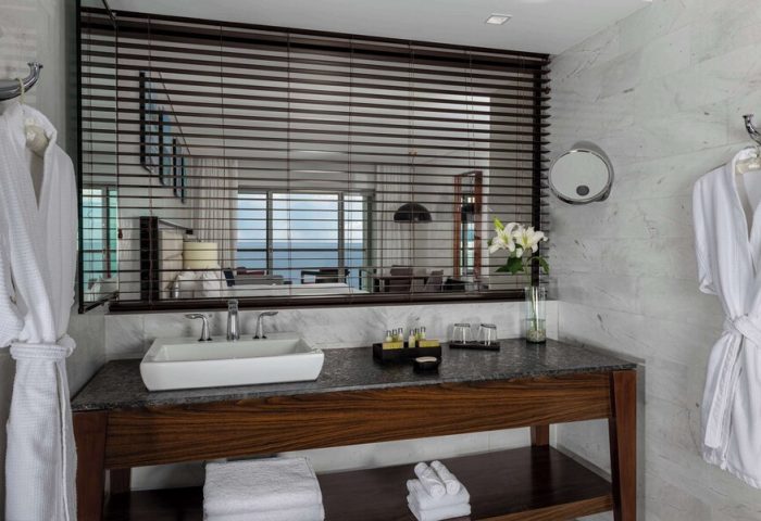 Bathroom at Hilton Vallarta Riviera All-Inclusive Resort, a gay-friendly hotel. The room has a sink, mirror, and robes.
