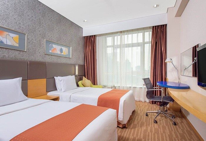 Holiday Inn Express Beijing Dongzhimen, gay-friendly hotel. Room with two beds, desk, chair, and window. Modern design for gay travelers.