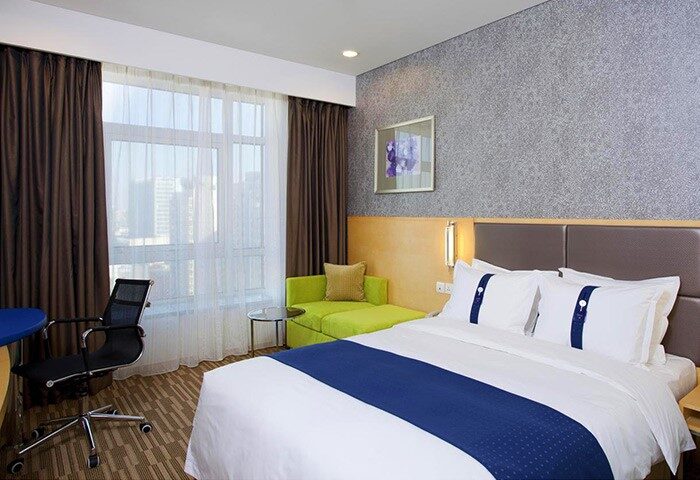 Holiday Inn Express Beijing Dongzhimen room. Gay-friendly hotel with bed, desk, sofa, and city view. Ideal for gay travelers in Beijing.