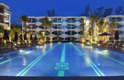 Holiday Inn Express Krabi Ao Nang Beach pool at night. Gay-friendly hotel with illuminated pool, palm trees, and lounge chairs. Serene Krabi vacation.