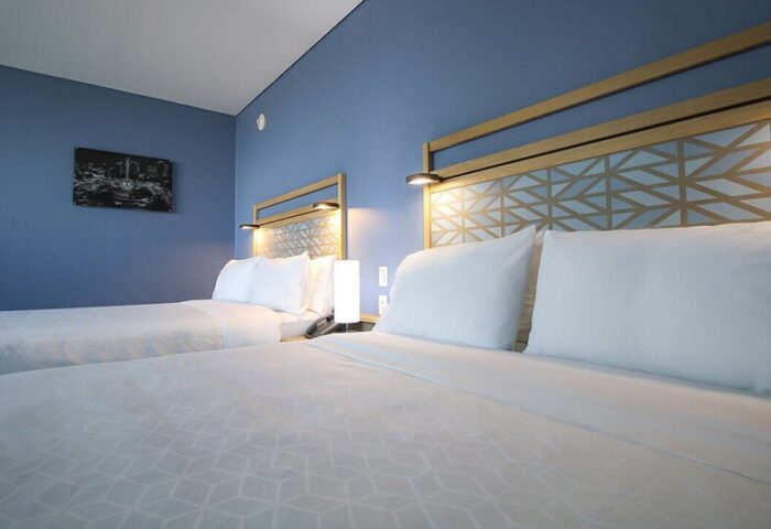 Holiday Inn Express Mexico Reforma gay-friendly hotel room. Two beds with geometric headboards, blue wall, and modern decor.