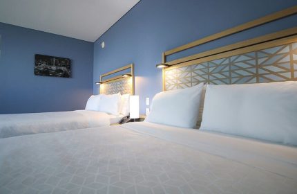 Holiday Inn Express Mexico Reforma gay-friendly hotel room. Two beds with geometric headboards, blue wall, and modern decor.