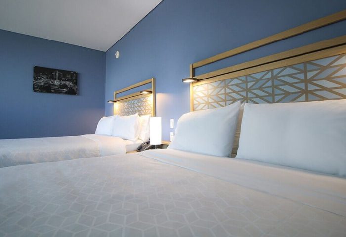 Holiday Inn Express Mexico Reforma gay-friendly hotel room. Two beds with geometric headboards, blue wall, and modern decor.