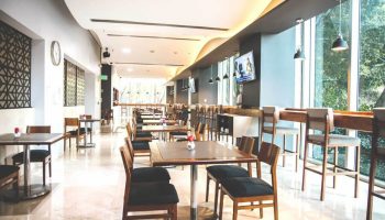 Holiday Inn Express Mexico Reforma gay-friendly hotel restaurant. Tables and chairs in a bright, modern dining area. Bar seating by large windows.