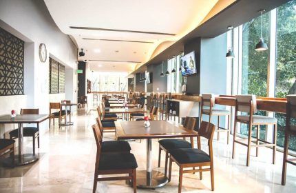 Holiday Inn Express Mexico Reforma gay-friendly hotel restaurant. Tables and chairs in a bright, modern dining area. Bar seating by large windows.