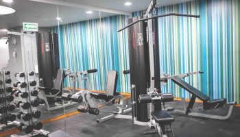 Holiday Inn Express Mexico Reforma gay-friendly hotel gym. Dumbbells, weight machines, and striped wall. Fitness center for gay travelers.