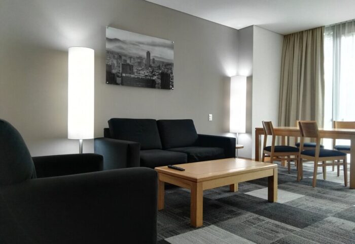 Holiday Inn Express Mexico Reforma gay-friendly hotel suite. Living area with sofa, chair, table, and dining set for a comfortable stay.