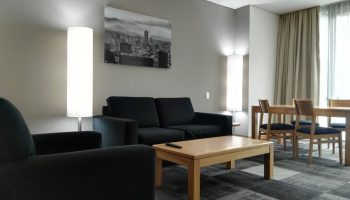 Holiday Inn Express Mexico Reforma gay-friendly hotel suite. Living area with sofa, chair, table, and dining set for a comfortable stay.