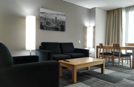 Holiday Inn Express Mexico Reforma gay-friendly hotel suite. Living area with sofa, chair, table, and dining set for a comfortable stay.