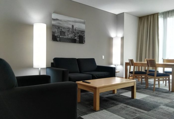 Holiday Inn Express Mexico Reforma gay-friendly hotel suite. Living area with sofa, chair, table, and dining set for a comfortable stay.