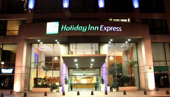 Holiday Inn Express Mexico Reforma, a gay-friendly hotel. Facade view at night with blue lights. Great for gay travel in Mexico City.