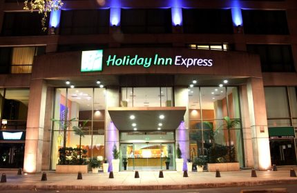 Holiday Inn Express Mexico Reforma, a gay-friendly hotel. Facade view at night with blue lights. Great for gay travel in Mexico City.