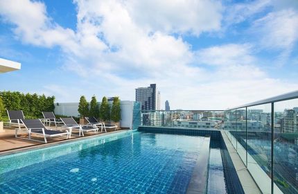 Rooftop pool at Holiday Inn Express Pattaya Central, a gay-friendly hotel. Loungers, city view, blue sky. Ideal for gay travel in Pattaya.