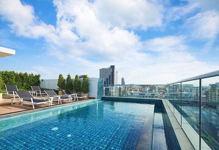 Rooftop pool at Holiday Inn Express Pattaya Central, a gay-friendly hotel. Loungers, city view, blue sky. Ideal for gay travel in Pattaya.
