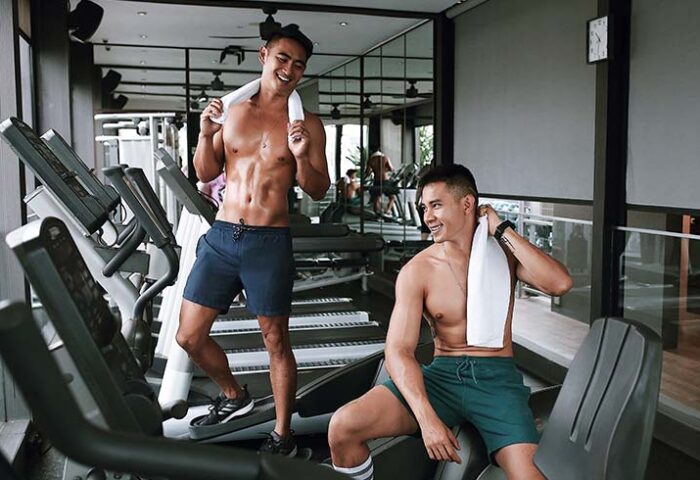 Holiday Inn Express Singapore Clarke Quay gym. Two gay men with towels, shirtless, working out. Gay-friendly hotel in Singapore.