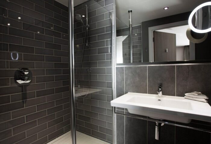 Holiday Inn Manchester City Centre gay-friendly hotel bathroom. Features a walk-in shower, modern sink, and illuminated mirror.