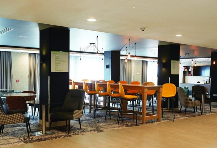 Holiday Inn Manchester City Centre's stylish lounge area. A gay-friendly hotel with modern decor, tables, and chairs for relaxing.