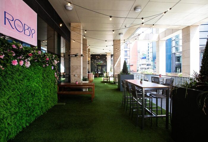 Holiday Inn Manchester City Centre's outdoor terrace. A gay-friendly hotel with tables, chairs, and greenery, perfect for relaxing.