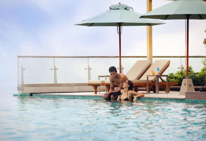 Holiday Inn Pattaya gay-friendly hotel pool scene. Couple relaxing by the infinity pool, enjoying the view. Perfect for gay travel in Pattaya.